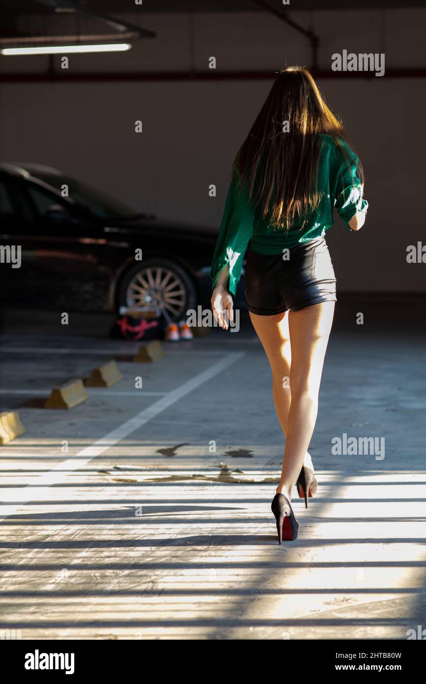 Vertical back view of a young attractive female with shots in a parking ...