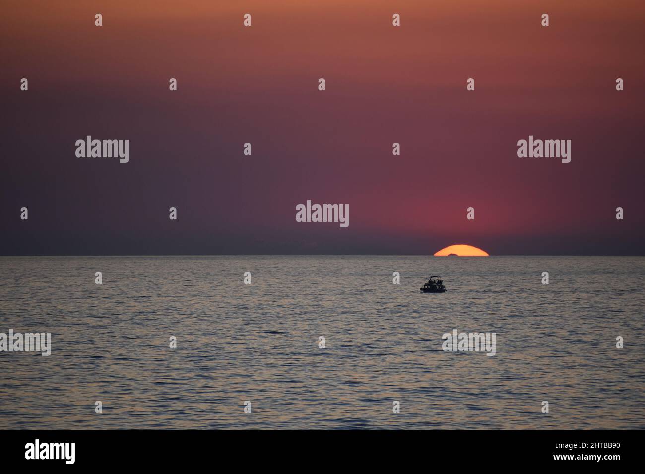 Beautiful golden pink sunset over the ocean with a boat in the water ...