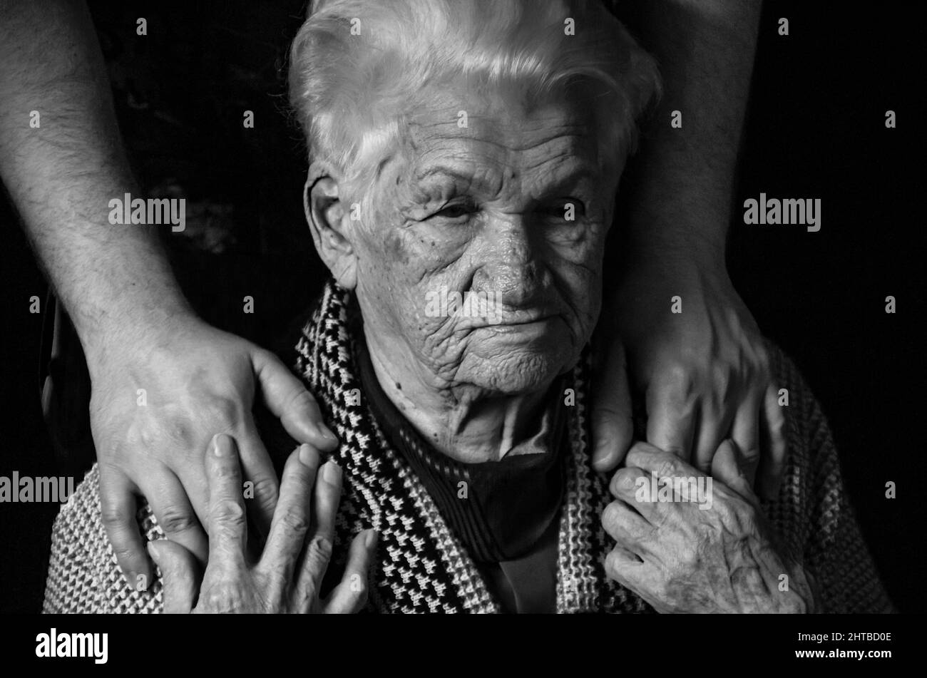 Hands of an elderly woman against black background. black and white photo. Stock Photo
