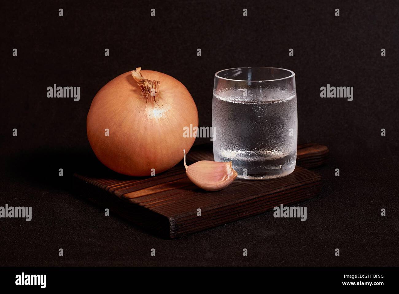 A glass of vodka, onion and garlic on a wooden stand Stock Photo Alamy