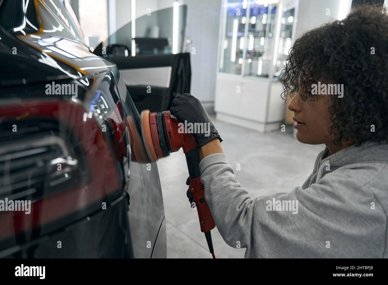 Concentrated car detailer buffing customer vehicle with orbital polisher Stock Photo