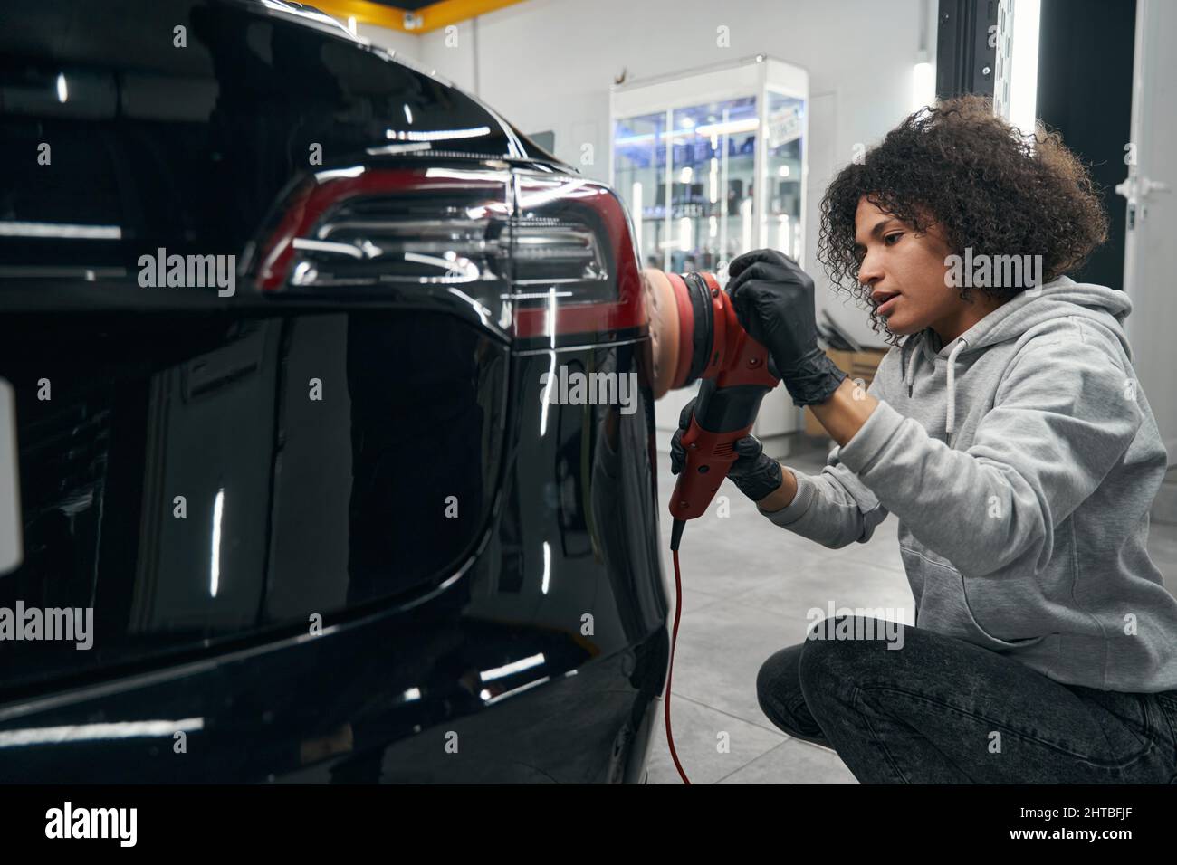 Experienced worker buffing motor vehicle with polisher Stock Photo
