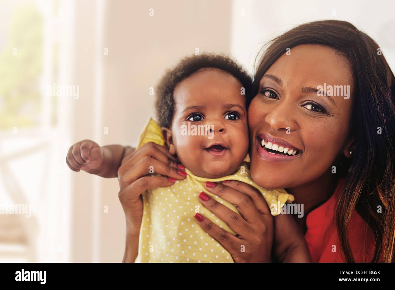 Can you see where she got her good looks from. Portrait of a mother holding up her baby girl. Stock Photo
