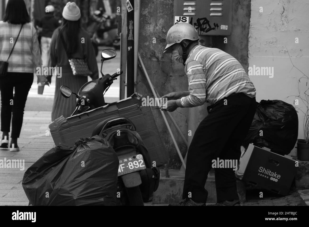 Greyscale view of a worker in a mask picking the garbage in Tainan, Taiwan Stock Photo