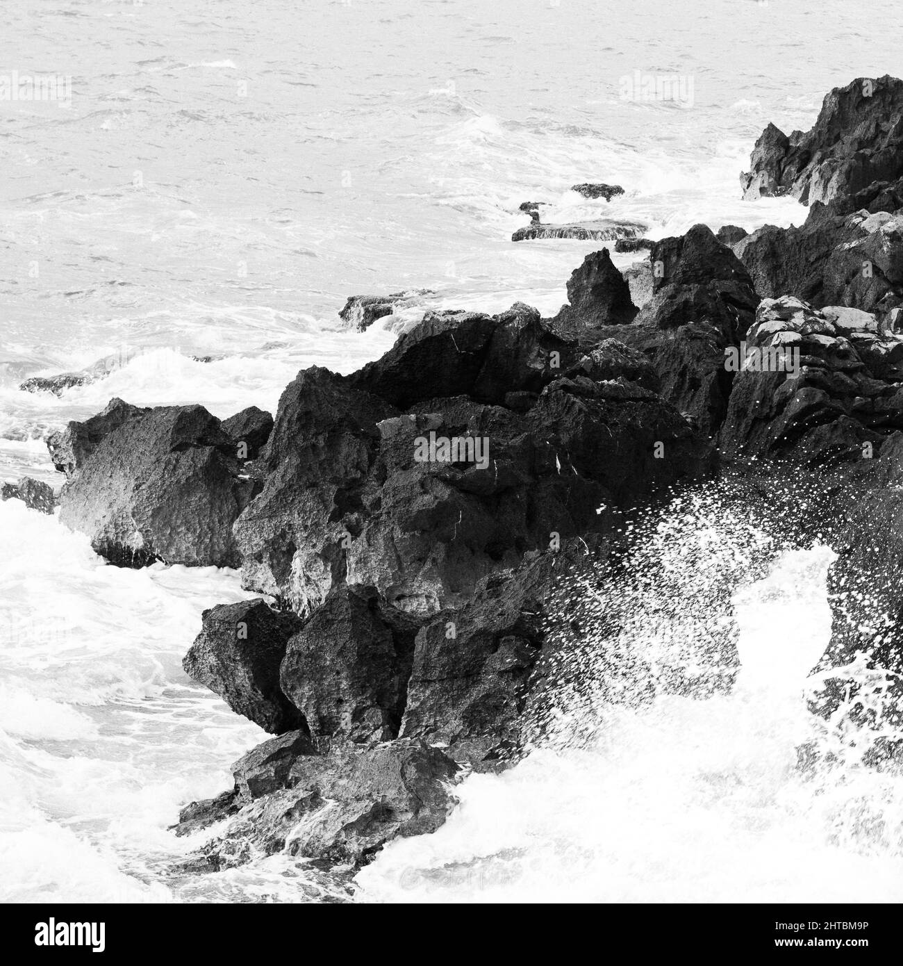 Grayscale of a rocky shore under the blue sky Stock Photo - Alamy