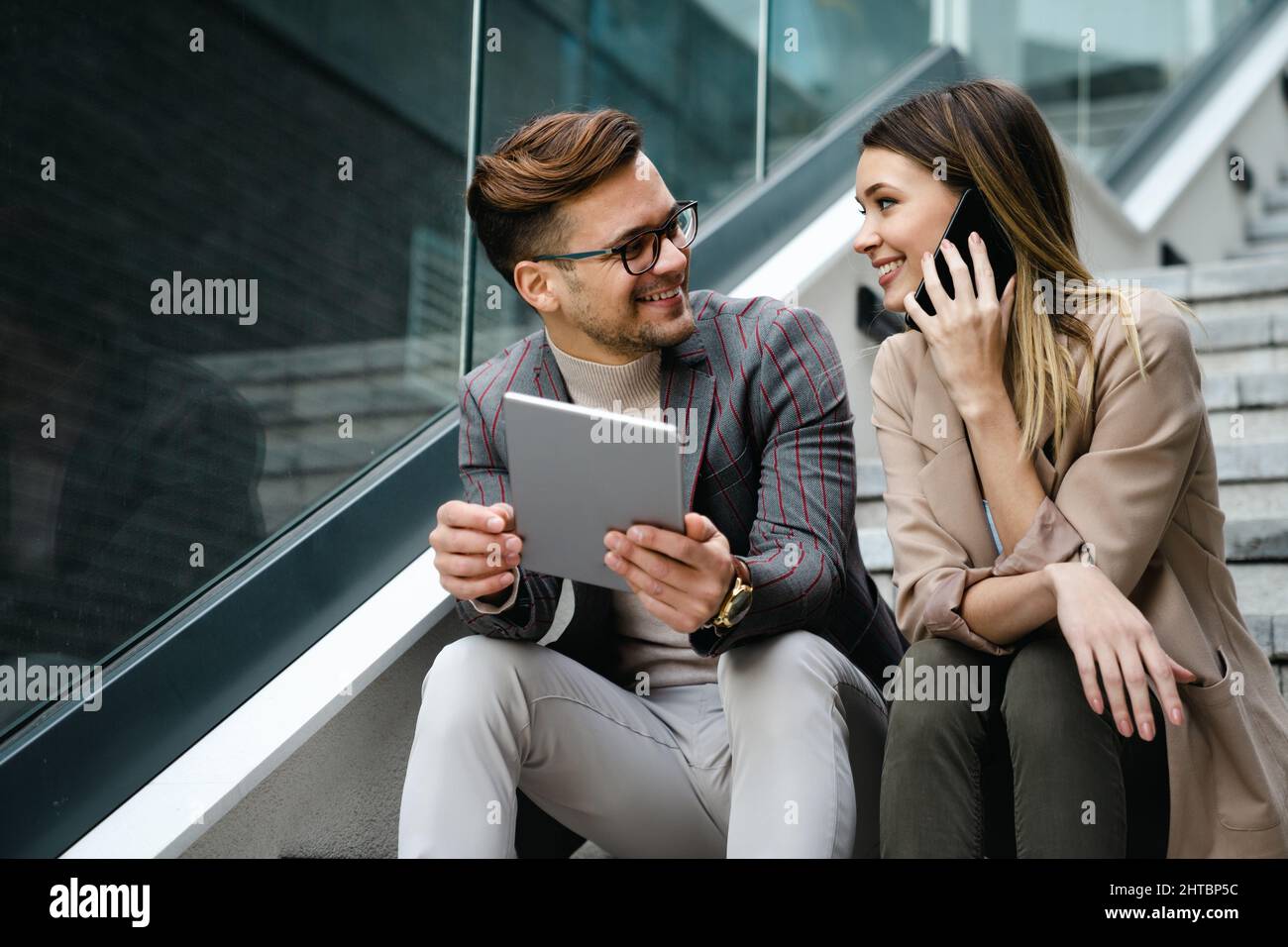 Successful young business people talking, working together in front of modern business building Stock Photo