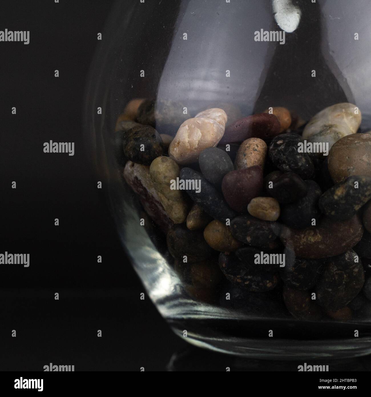 A closeup of a small decorative glass vase filled with pebbles isolated