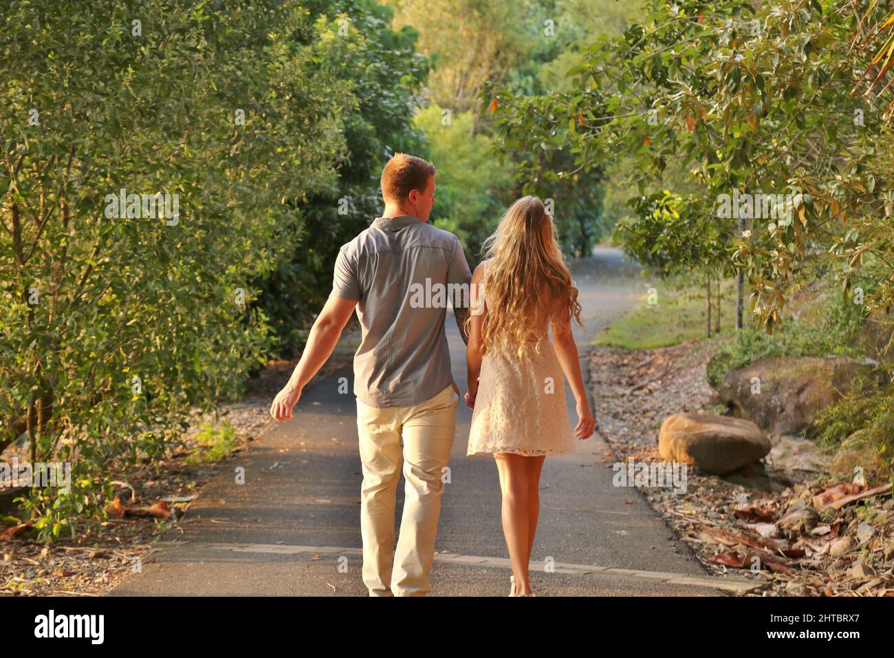 Back view of a young couple holding hands and walking in a park Stock ...