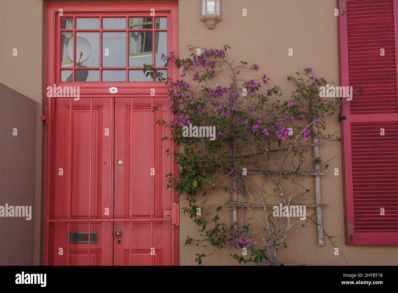Beautiful building facade with a red door and climbing plant Stock Photo