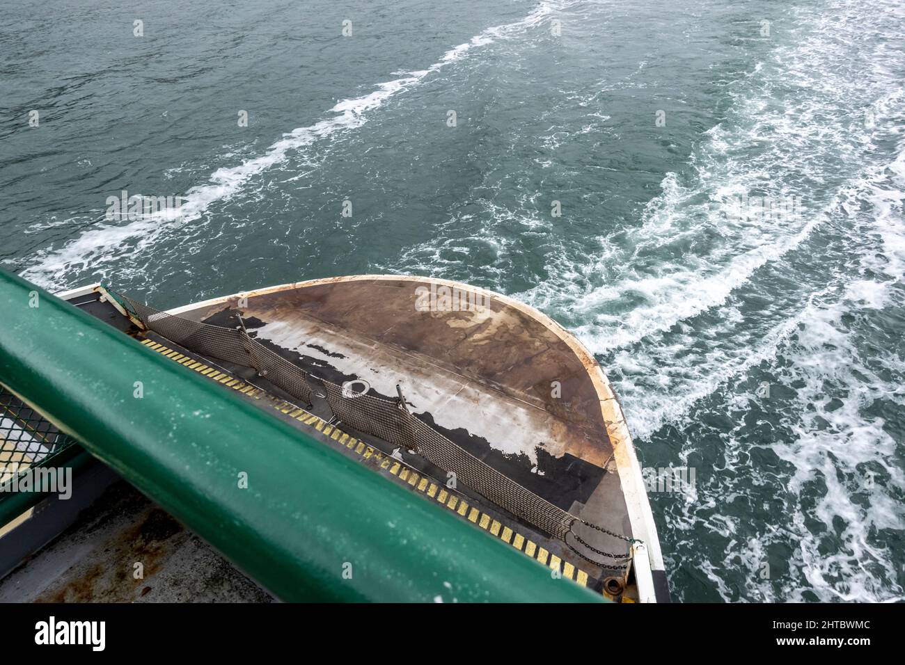 High angle view of the back of a Washington state ferry making its route to San Juan Island, waking the ocean water behind it on an overcast, rainy da Stock Photo
