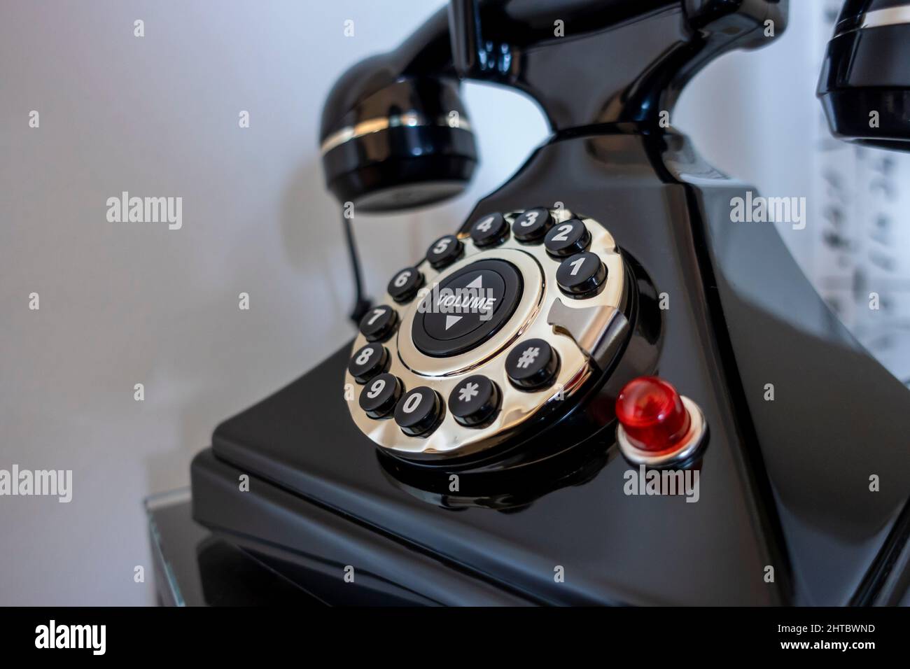 Angled selective focus on a black rotary phone on a bedroom nightstand, shot against a white background Stock Photo