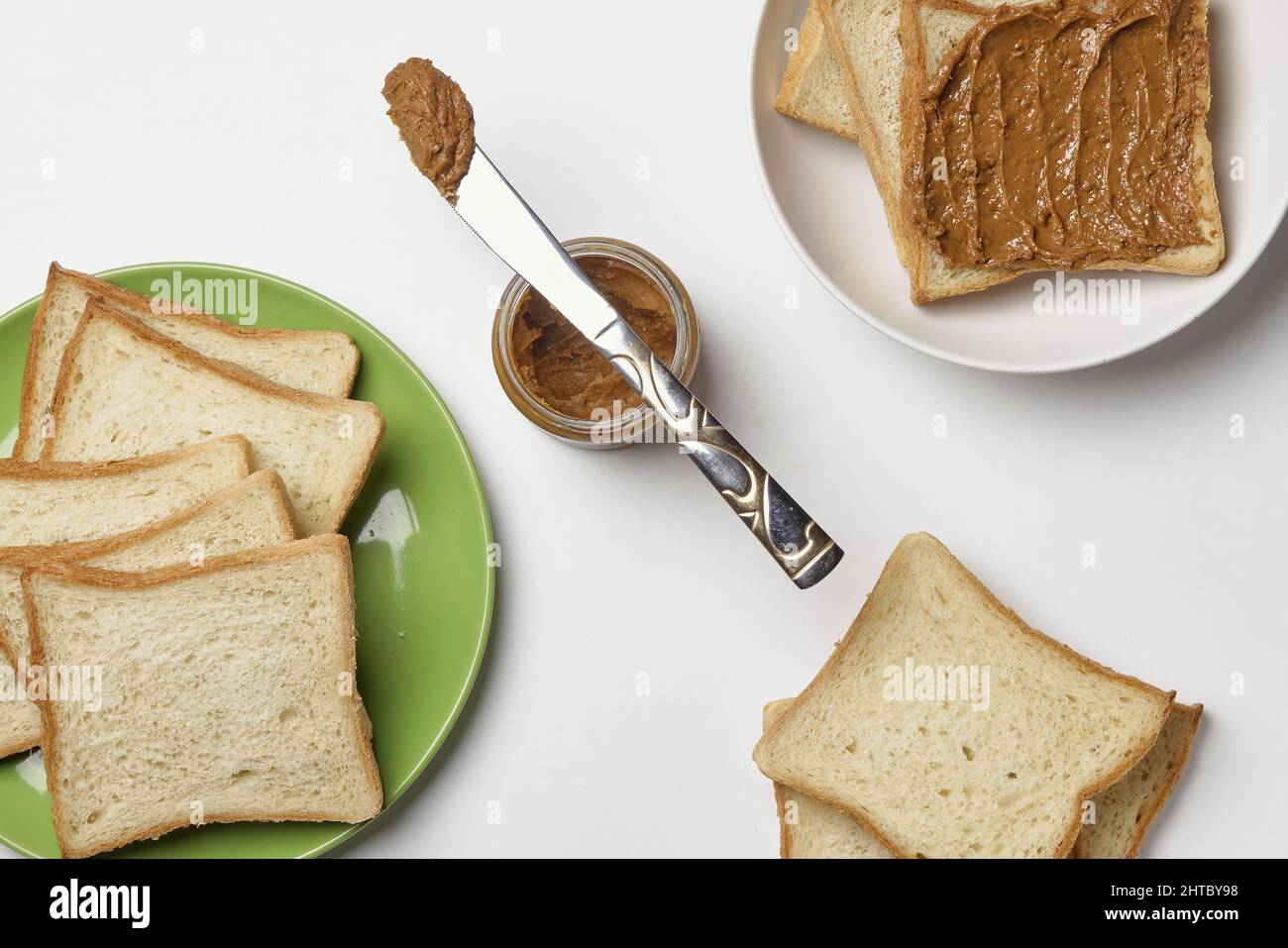 Knife on the peanut butter jar and fresh toasts on the plates over the