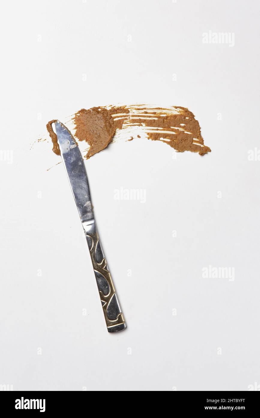 Vertical shot of the knife buttering the tasty peanut butter on the white  surface Stock Photo by wirestock