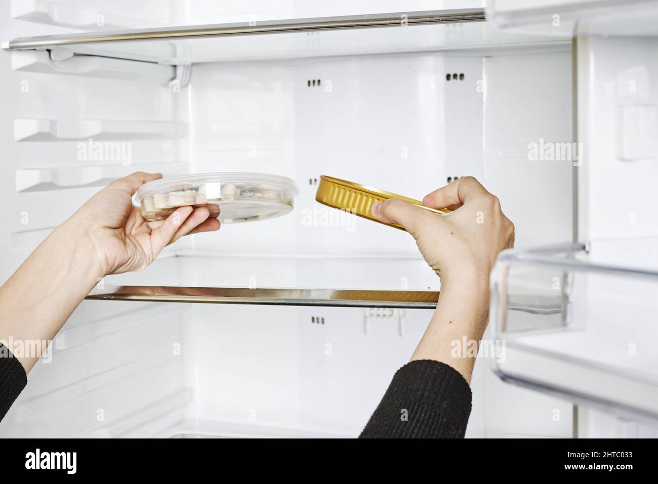 Closeup shot of female hands putting food in containers to the empty