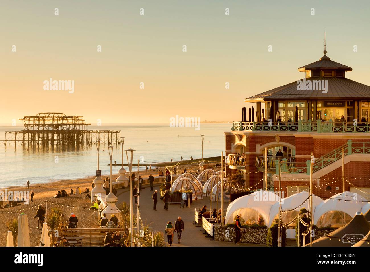 13 January 2022: Brighton, East Sussex, UK - Winter on the promenade at Brighton, with people enjoying late afternoon sunshine, and the old West Pier Stock Photo