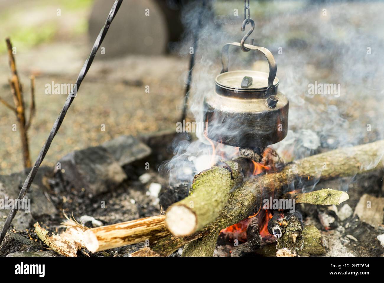 https://c8.alamy.com/comp/2HTC684/closeup-shot-of-the-outdoor-fire-pit-and-the-tea-kettle-hanging-and-boiling-in-the-forest-2HTC684.jpg