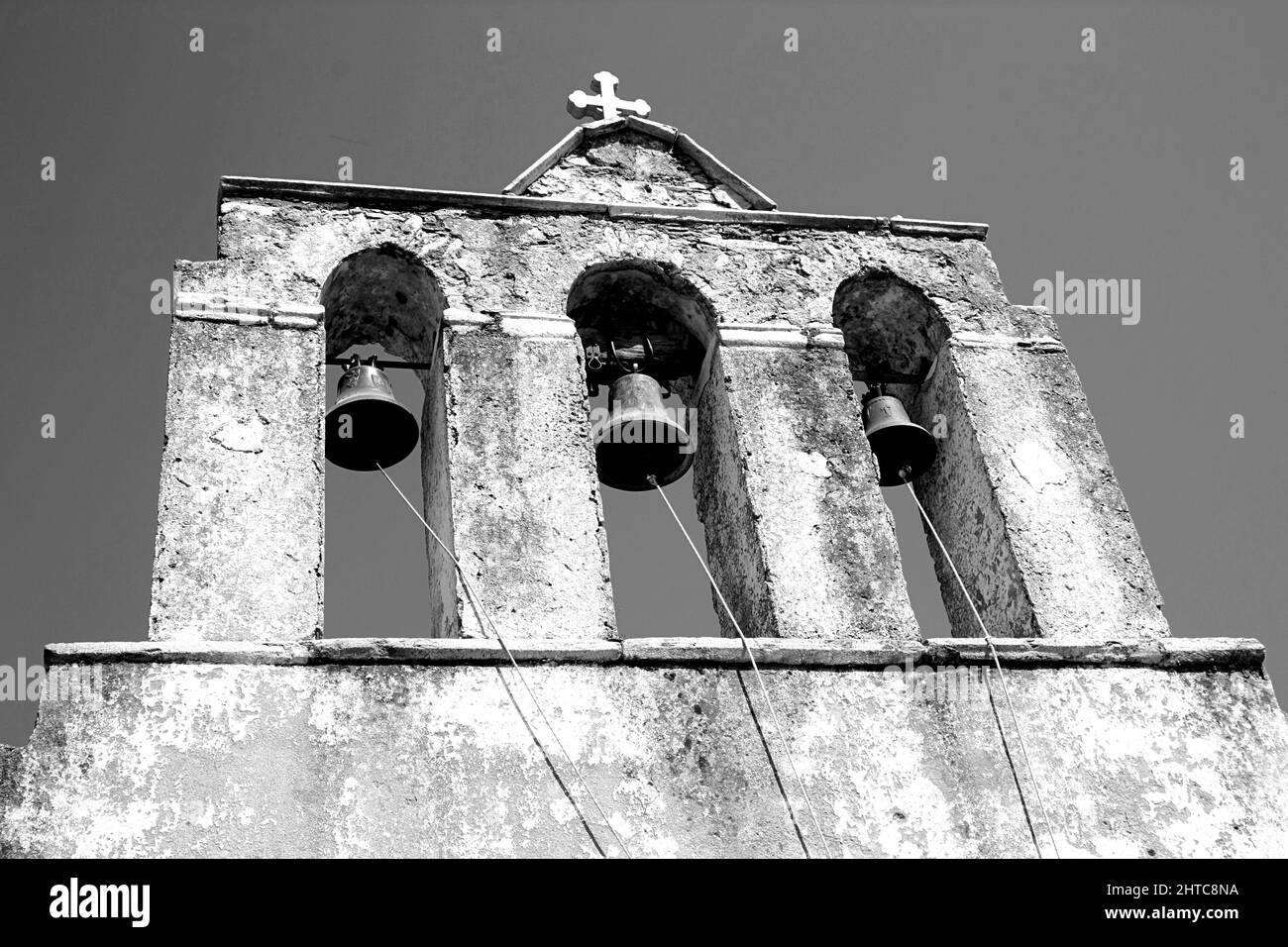 Grayscale low angle view of church bells with a cross in the top in the ...