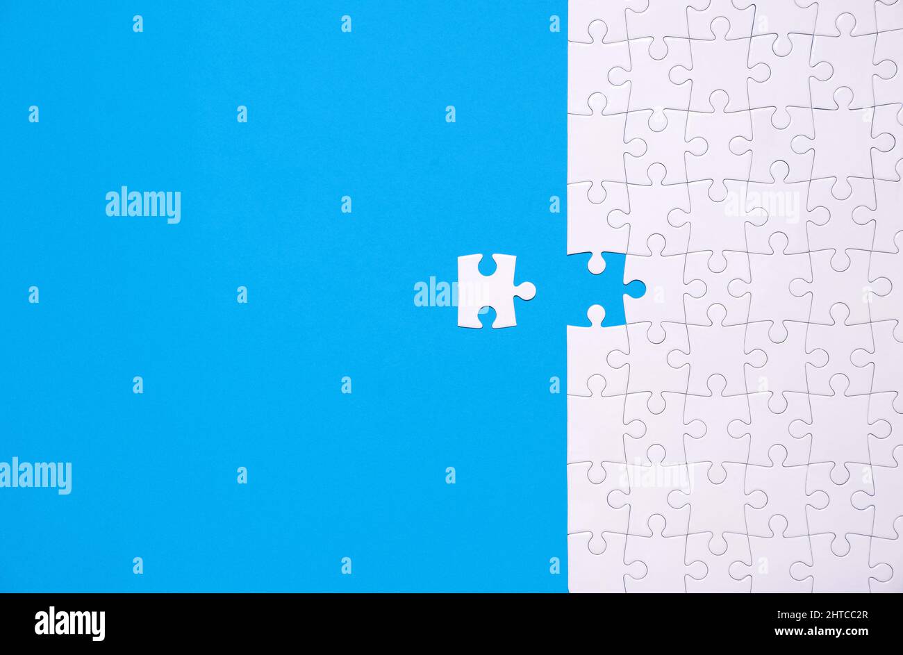 Unfinished white jigsaw puzzle isolated on blue background with copy space Stock Photo