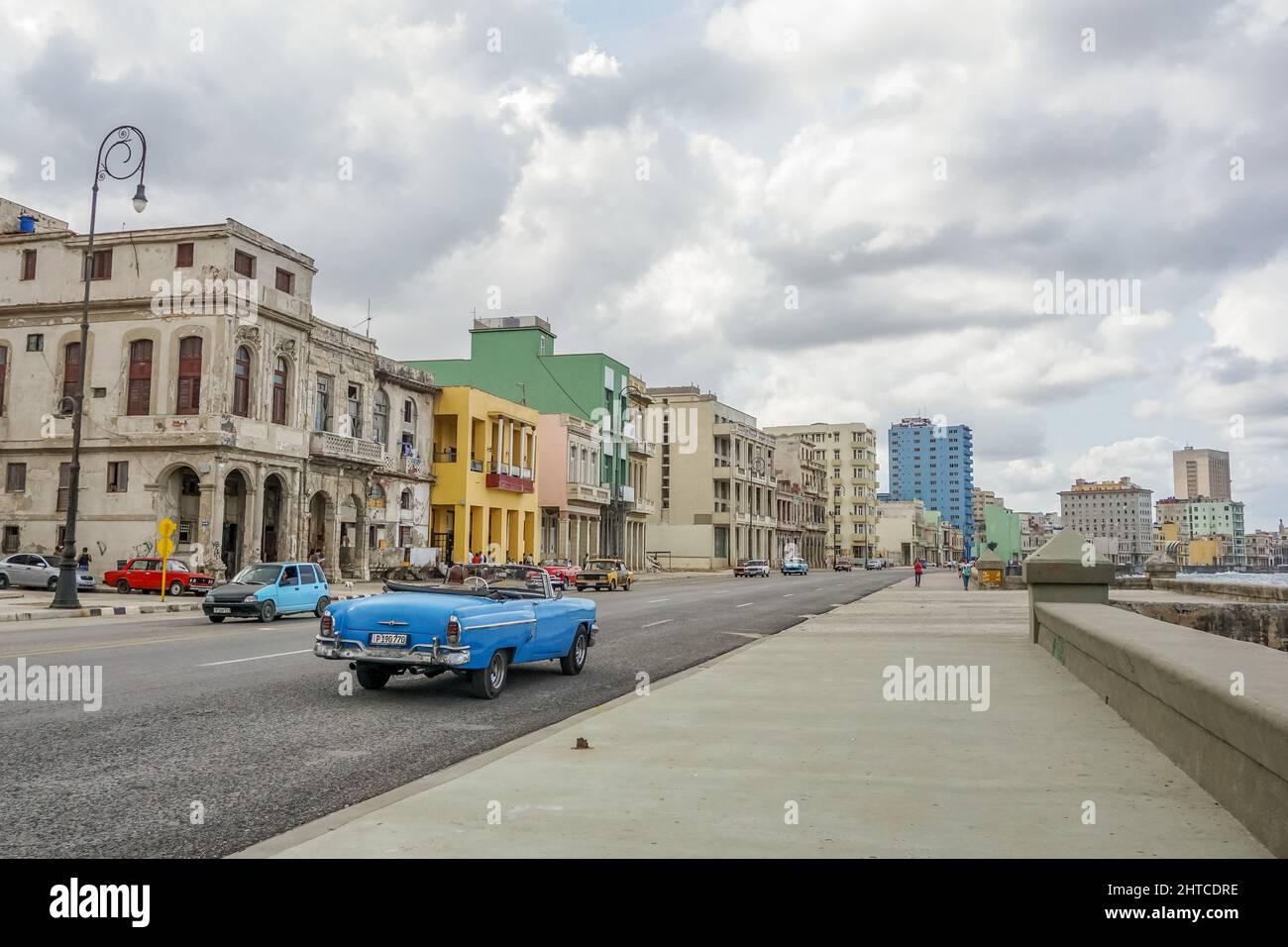 Road in Havana, Cuba, with colorful classic cars driving under the cloudy sky Stock Photo