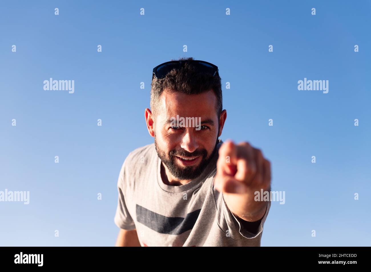 bearded man pointing finger at camera with blue sky in background, copy space for text Stock Photo