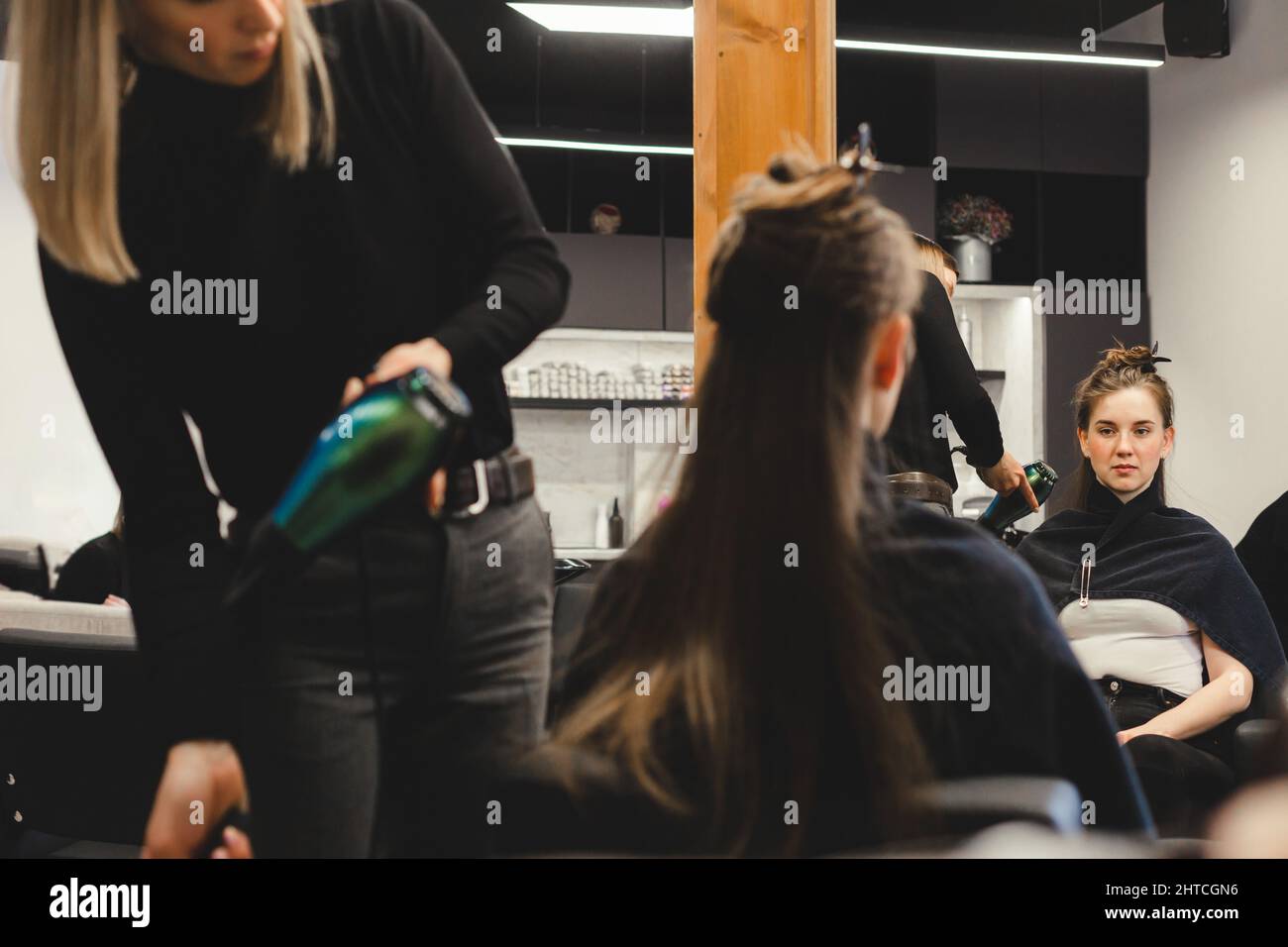 Master woman hairdresser dries the girl's hair with a hairdryer after ...