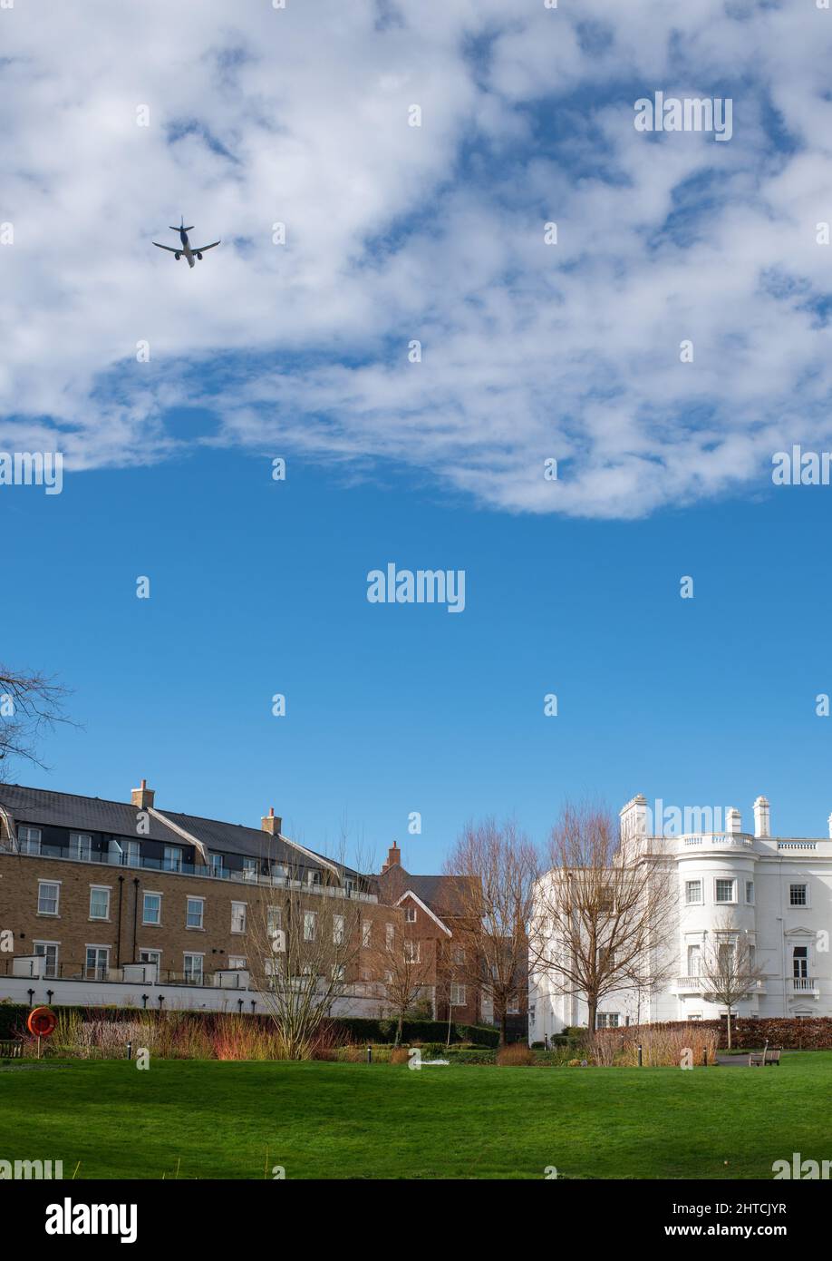 Gated housing development under the flightpath to London Heathrow cannot keep out the airplane heading to the airport. Stock Photo