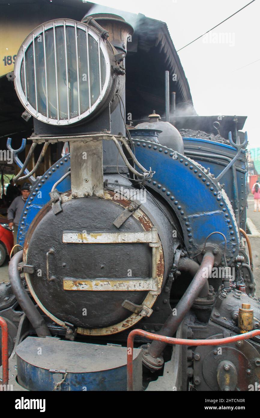 Vertical shot of a rusted train in Darjeeling, India with steam coming out of it Stock Photo