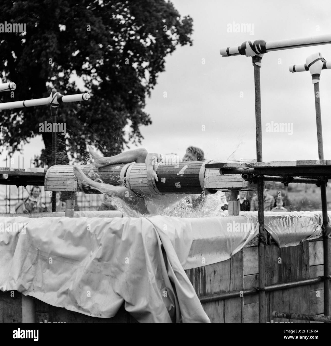Laing Sports Ground, Rowley Lane, Elstree, Barnet, London, 11/06/1988. A man falling off a spinning balance beam into a tank of water, part of the 'It's a Knockout' competition at the 1988 Family Day at Laing's Sports Ground. Attractions at that year's Family Day included; a parade of vintage cars, helicopter rides, plate smashing, stalls, an 'It's a Knockout' style competition and tennis and six-a-side football tournaments.  The event was opened by John Conteh, former world light heavy weight champion and ended with a barbecue and disco. The 'It's a Knockout' competition was won by a team fro Stock Photo