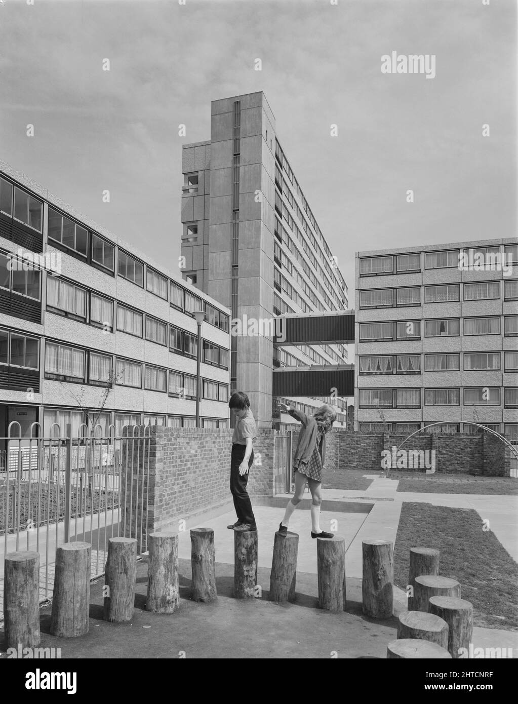 Pooles Park, Finsbury Park, Islington, London, 20/05/1970. Two children playing on posts in a playground besides blocks of flats at Pooles Park, built using the 12M Jespersen system. In 1963, John Laing and Son Ltd bought the rights to the Danish industrialised building system for flats known as Jespersen (sometimes referred to as Jesperson). The company built factories in Scotland, Hampshire and Lancashire producing Jespersen prefabricated parts and precast concrete panels, allowing the building of housing to be rationalised, saving time and money. The Pooles Park development was built by Lai Stock Photo