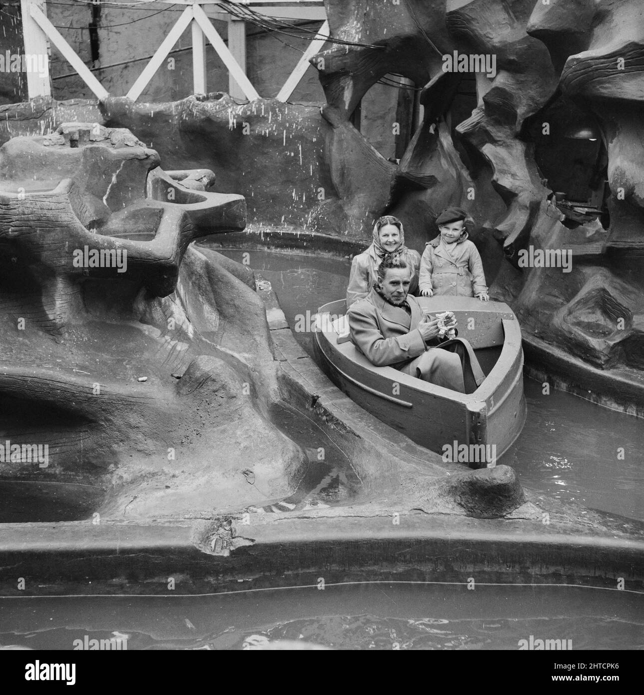 Skegness, East Lindsey, Lincolnshire, 22/05/1954. A couple and a young boy in a boat on a water ride during a Laing staff day trip to Skegness. In 1947, after a seven year break, Laing had resurrected their 'Area Outings' for staff and their families, with trips taking place in May and June. In 1954, there were seven outings planned to take place over five weeks in May and June. This trip to Skegness was for employees and their families from the Midlands and South Yorkshire. Stock Photo