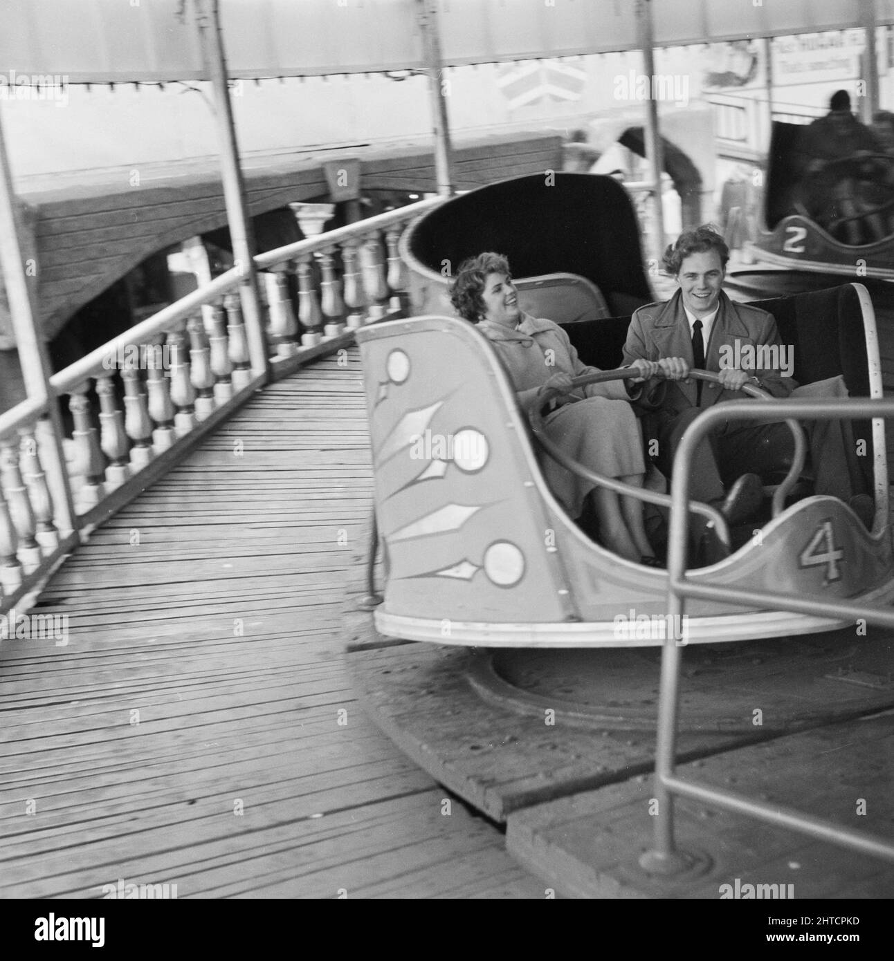 Skegness, East Lindsey, Lincolnshire, 22/05/1954. A man and a woman riding on a waltzer during a Laing staff trip to Skegness. In 1947, after a seven year break, Laing had resurrected their 'Area Outings' for staff and their families, with trips taking place in May and June. In 1954, there were seven outings planned to take place over five weeks in May and June. This trip to Skegness was for employees and their families from the Midlands and South Yorkshire. Stock Photo