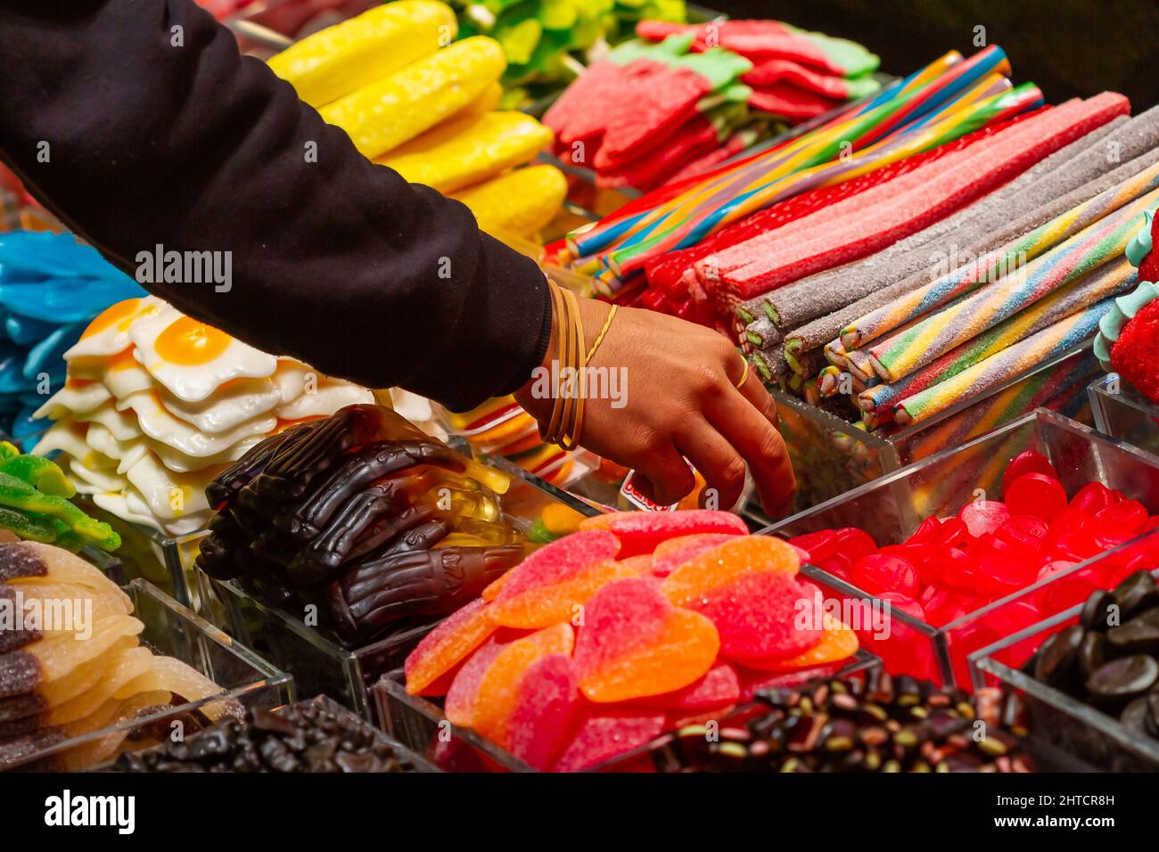 Hand grabbing candy in a store in Boqueria market in Barcelona, Spain Stock Photo