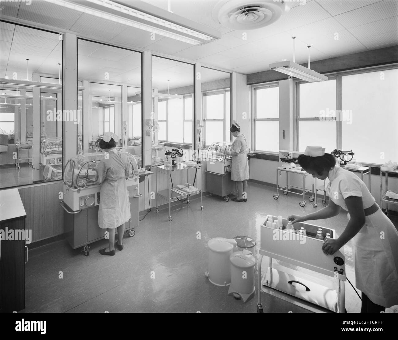 Walsgrave Hospital, Clifford Bridge Road, Walsgrave on Sowe, Coventry, West Midlands, 17/03/1967. Two nurses tend to babies in incubators whilst a third inspects a trolley of milk bottles in the After Care Unit at Walsgrave Hospital. Stock Photo
