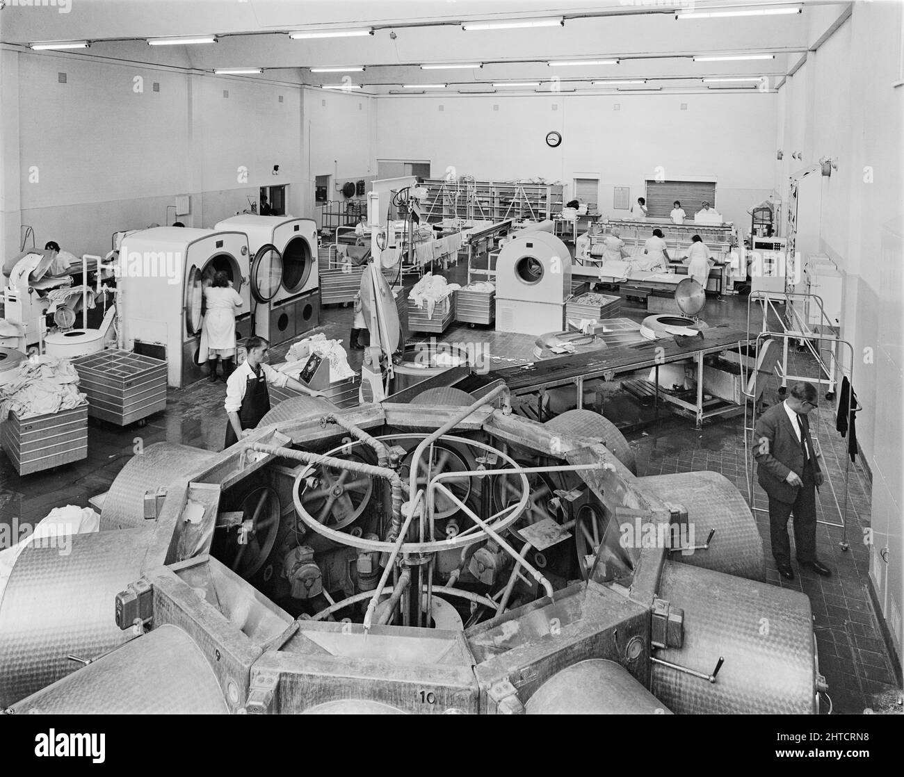 West Cumberland Hospital, Homewood Road, Homewood, Whitehaven, Copeland, Cumbria, 27/08/1964. Workers washing and pressing bed linen in the laundry at West Cumberland Hospital. Built during the first phase of construction at the site along with the boiler house and workshops, the laundry could handle 45,000 articles a week and serviced a number of hospitals in the region. This photograph appeared in the December 1964 issue of Team Spirit, the Laing company newsletter. Stock Photo