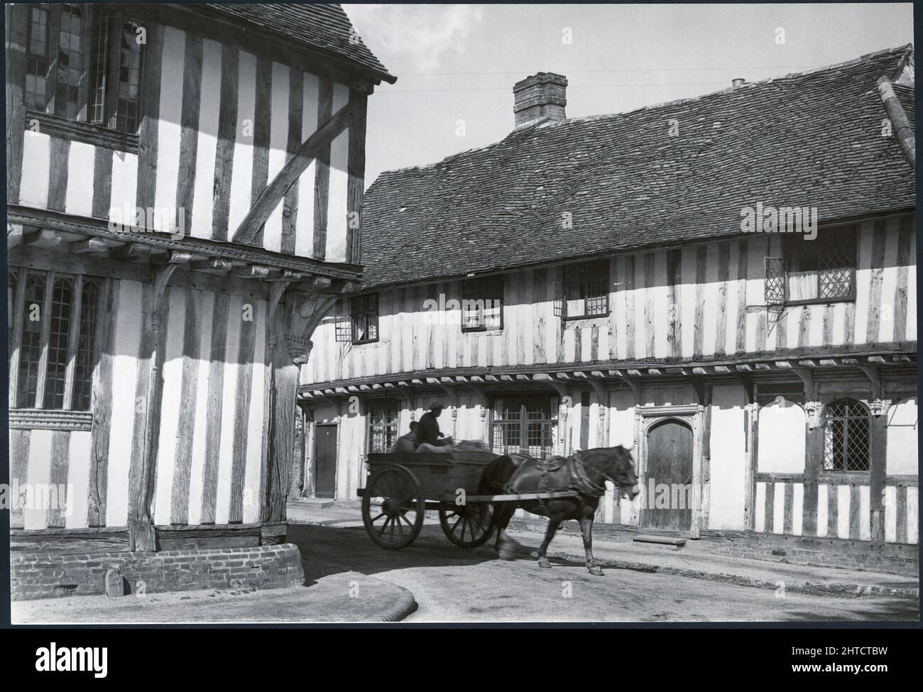 Lady Street, Lavenham, Lavenham, Babergh, Suffolk, 1925-1939. A horse and cart at the junction of Lady Street and Water Street with The old Wool Hall (on the left) and Tudor shops (on the right) Stock Photo