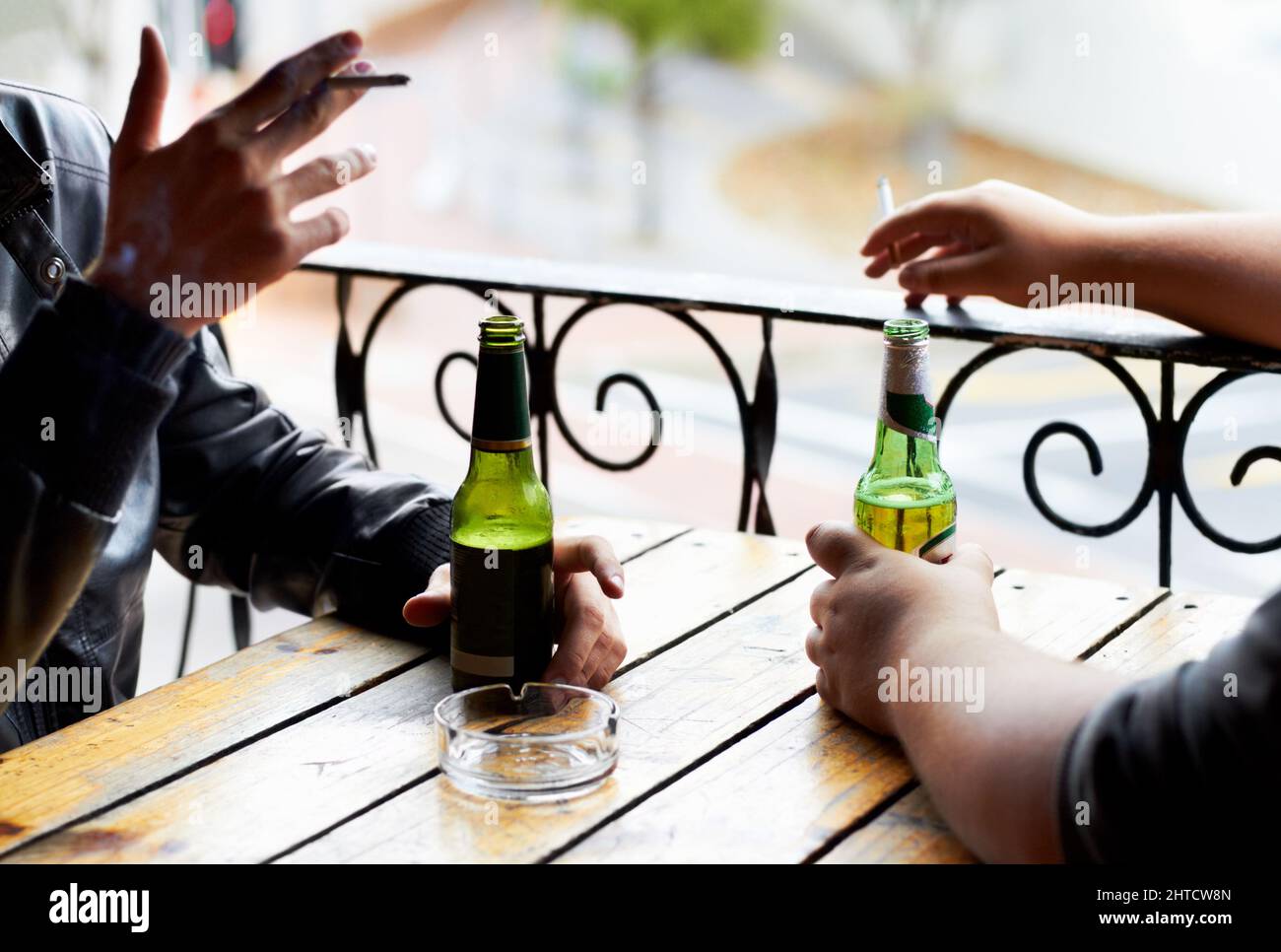 Sharing bad habits.... A cropped image of two young men smoking with beers in front of them. Stock Photo