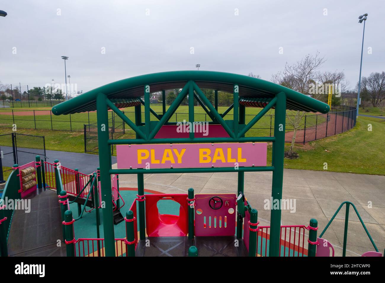 View of children's playground with a sign saying 'Play Ball' and a game field on the background Stock Photo