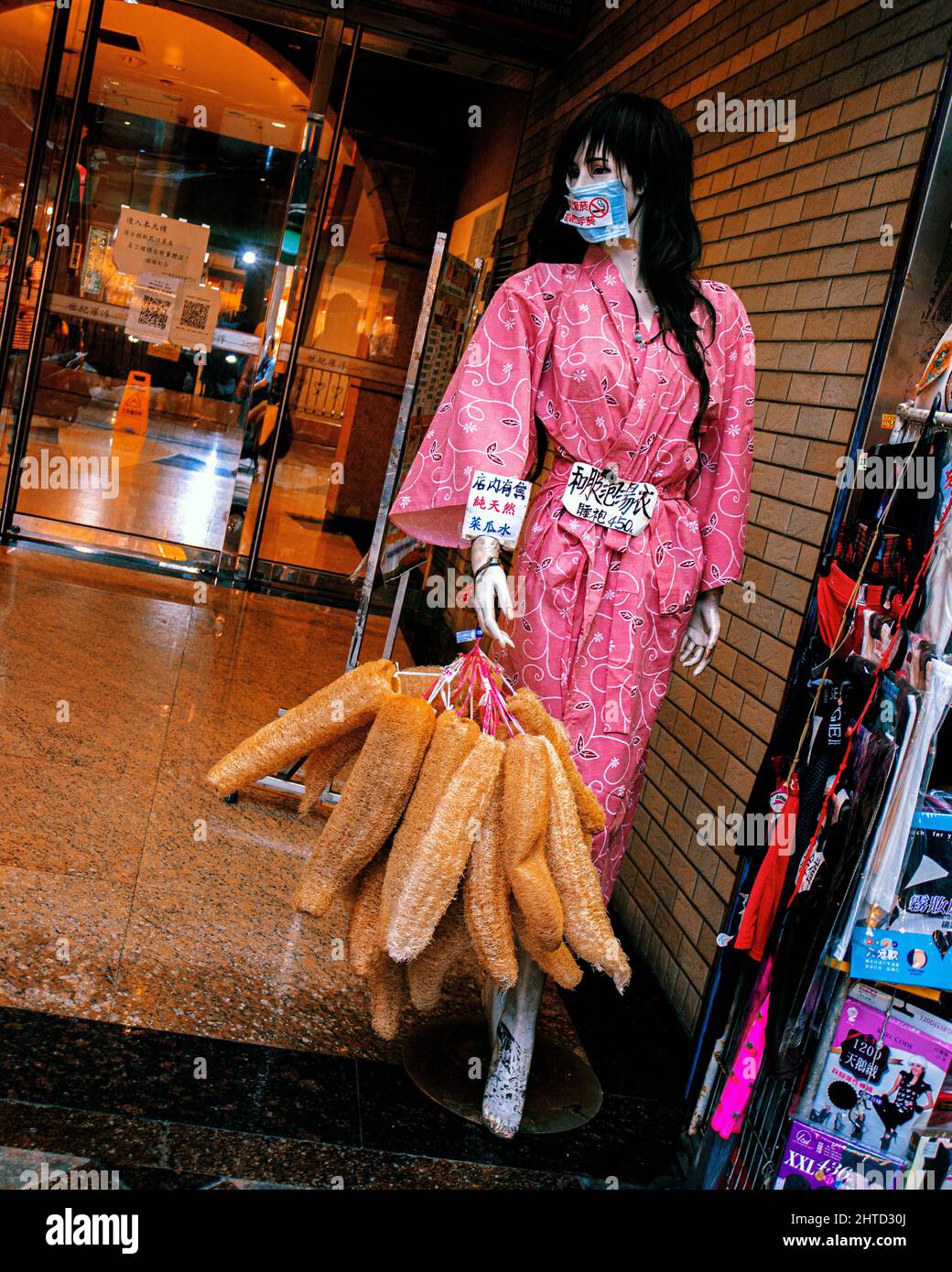 Vertical shot of a mannequin wearing a pink kimono and holding bags Stock Photo