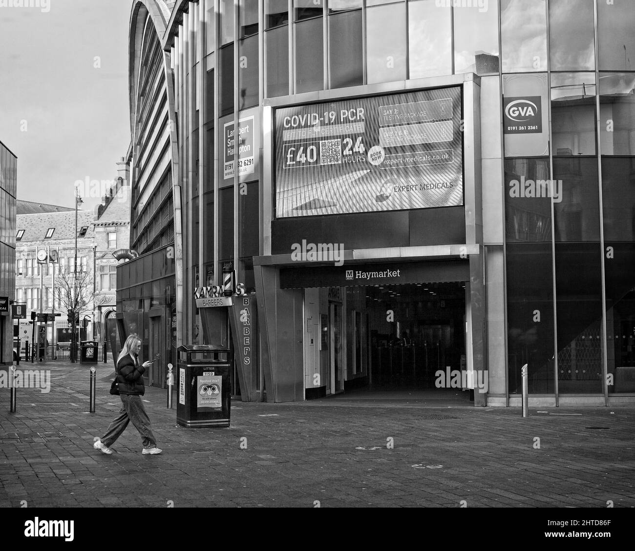 A young woman checks her phone as she walks in Newcastle city centre near the Haymarket Metro Station. Stock Photo
