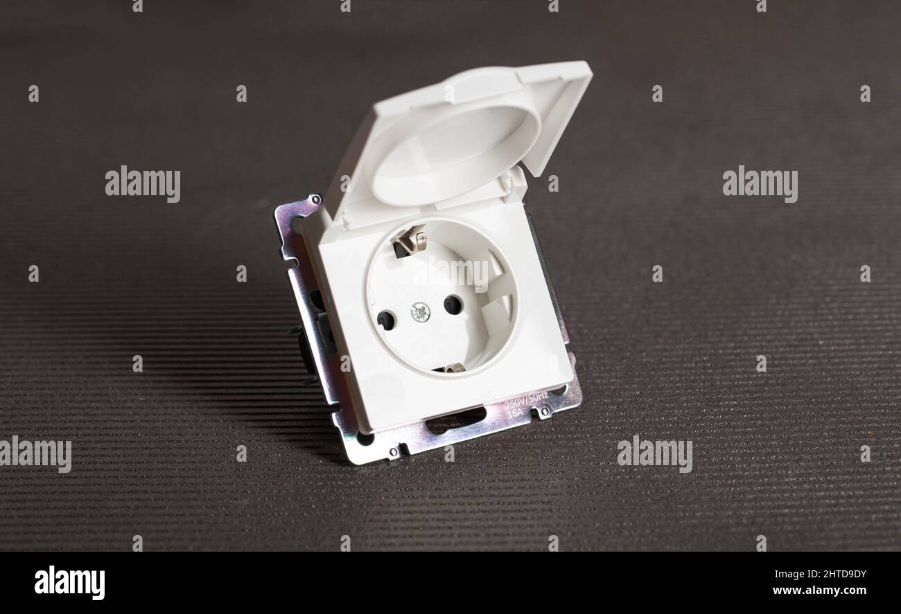 Socket with a protective cover against splashes on a gray background, close-up Stock Photo