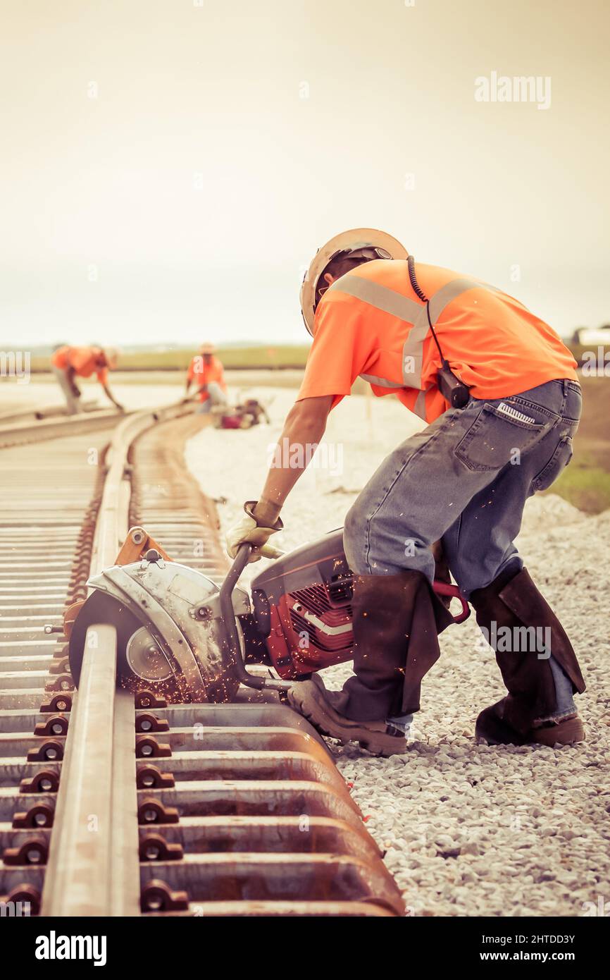 Workers in the process of railroad track construction rail saw with