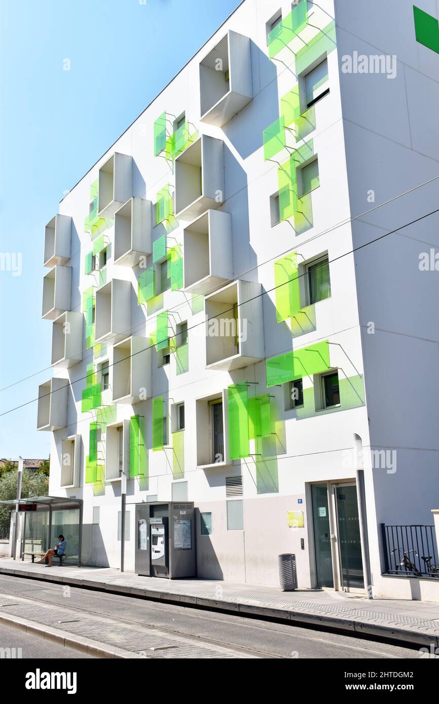 A small modern white six-storey apartment block with bright lime green glass panels and projecting boxes to some windows enlivening the facade. Stock Photo