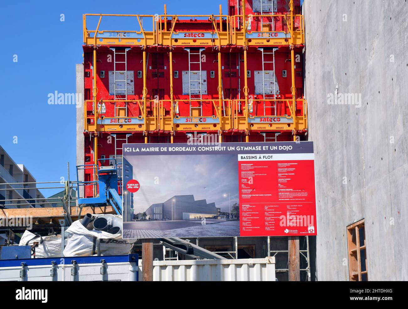 An unusually colourful building site, bright red reusable shuttering and orange guardrails and scaffolding, A gymnasium and a dojo being built. Stock Photo