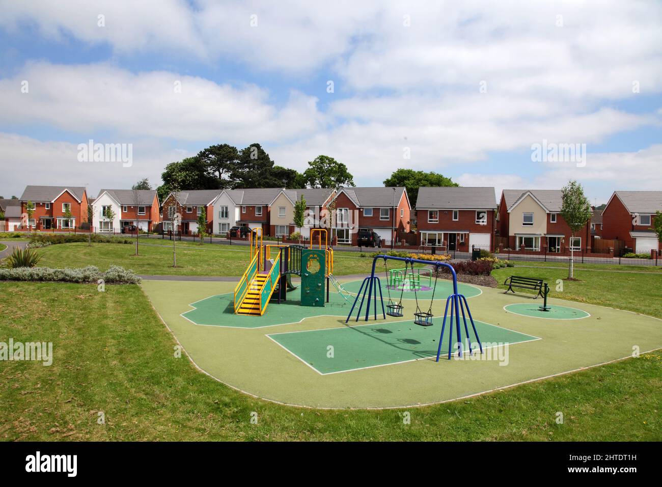 Green space and play area outside a modern housing estate development in Wolverhampton, West Midlands, UK, swings, slide,seats,climbing frame Stock Photo