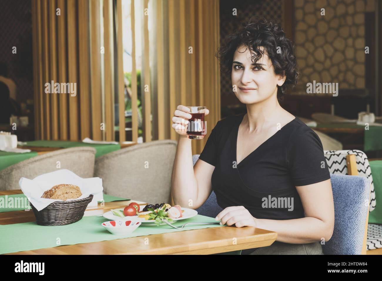 Photo of a white Caucasian woman drinking tea and having a meal in a