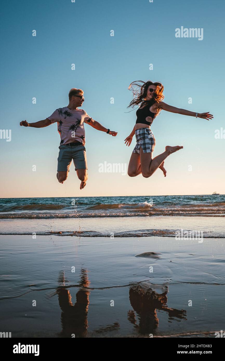 Happy young Caucasian couple jumping on a beach Stock Photo