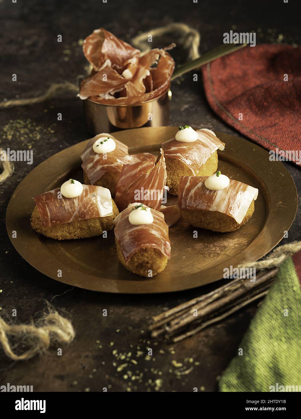 Closeup of Iberian ham croquettes with thin slices on top and kimchi