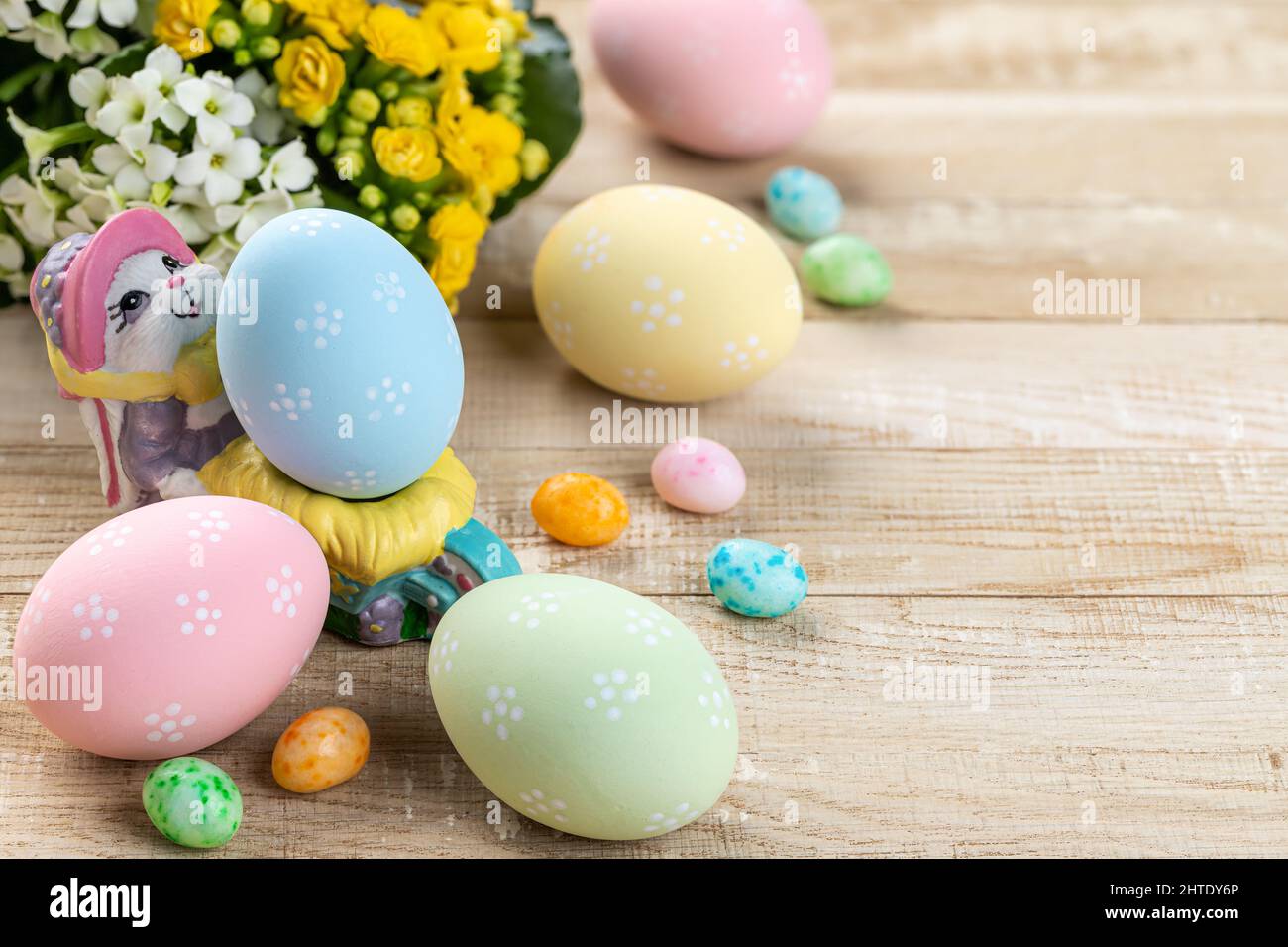 Colored easter eggs, candy and flowers on a rustic wooden table Stock Photo
