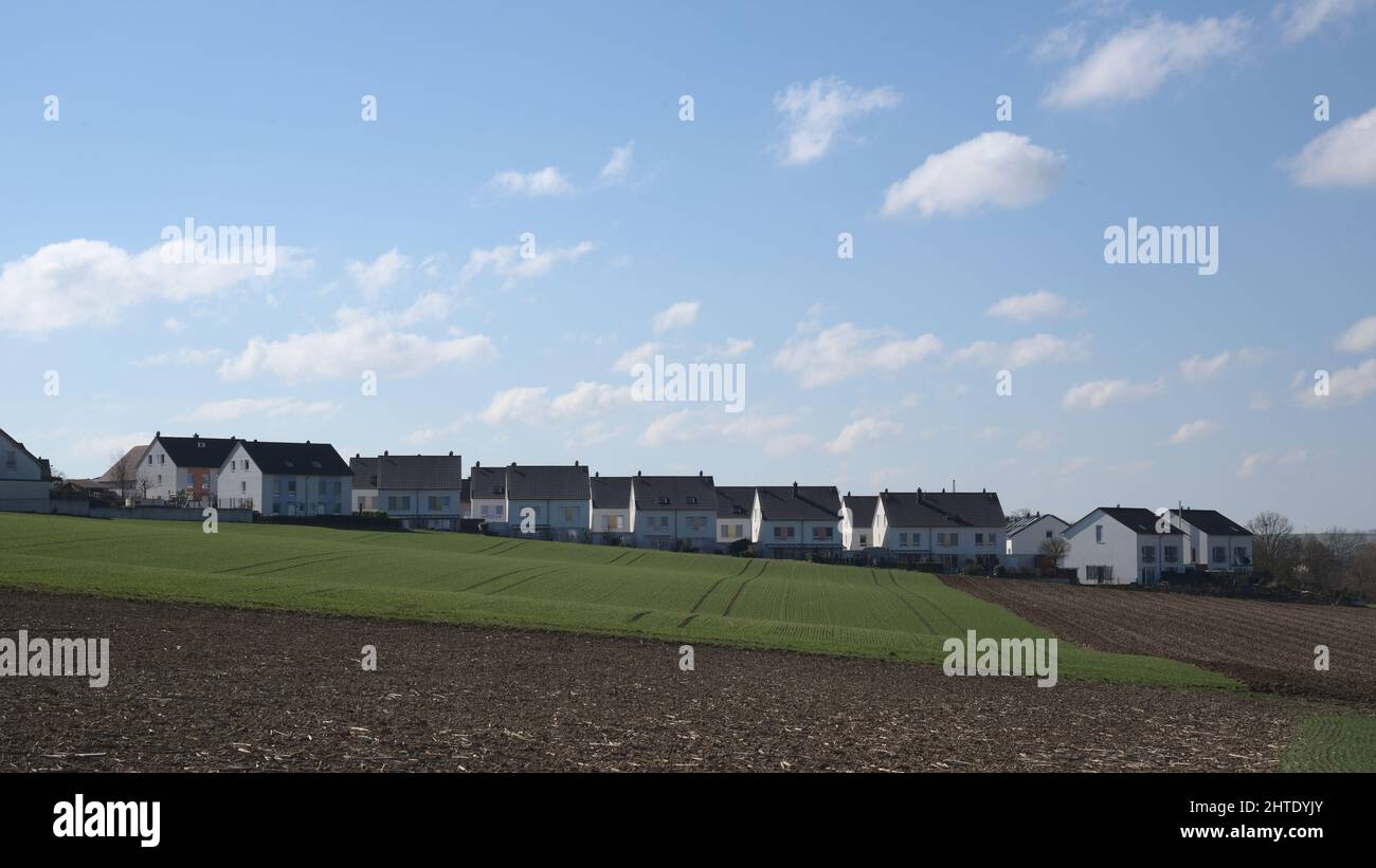 A row of newly built semi- detached houses on the horizon with blue cloudy sky. Stock Photo