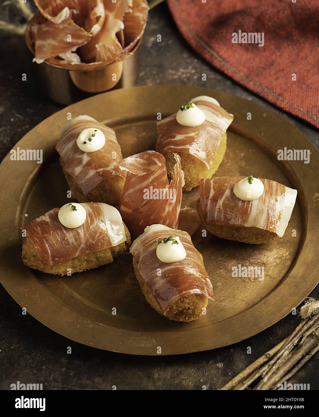 Closeup of Iberian ham croquettes with thin slices on top and kimchi